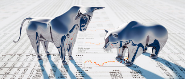 Bulle und Bär in Silber stehen auf einer Zeitung.Auf dieser ist der Dax Chart abgebildet.