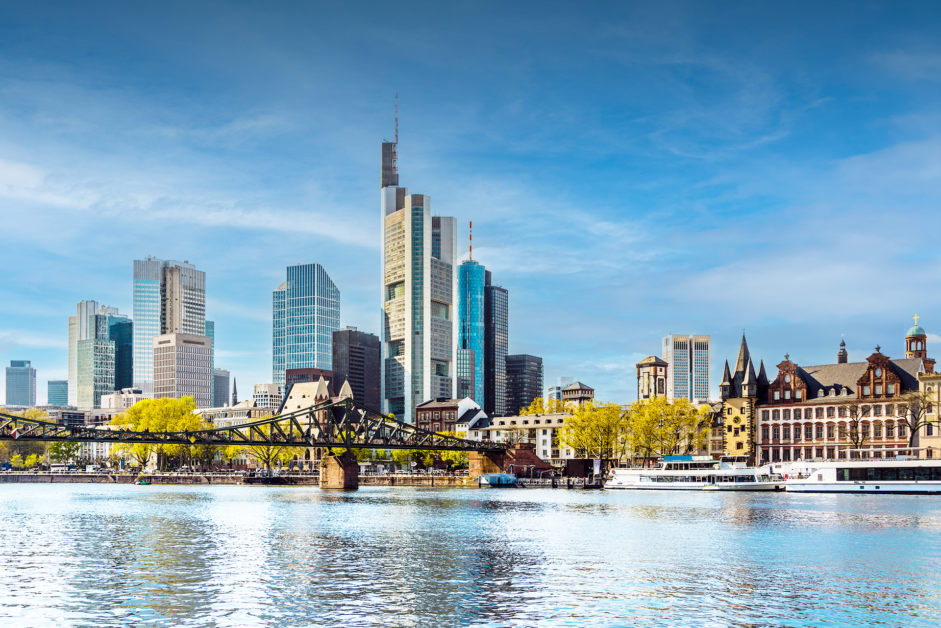 Die Skyline von Frankfurt und dem Main im Vordergrund bei blauen Himmel